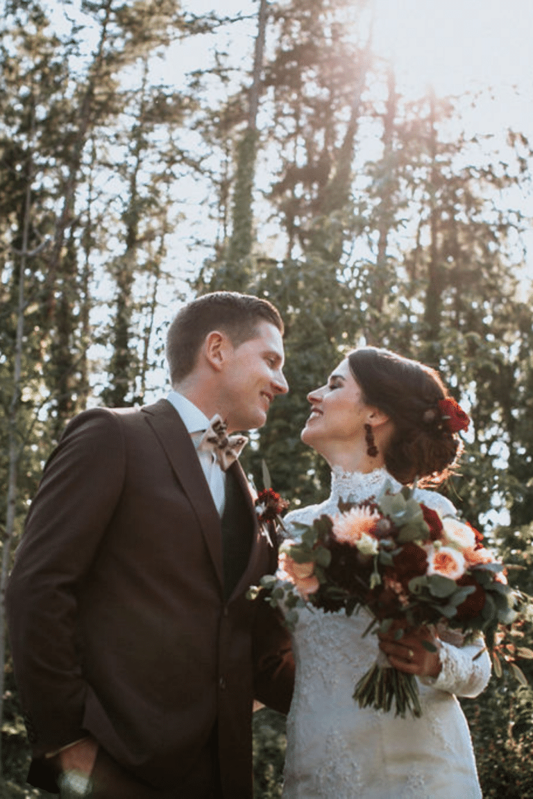 Brautpaar steht im Wald mit Blumenstrauß